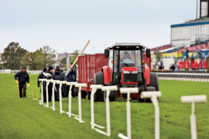 Workers remove temporary inside rails, set by a laser-guided tractor, on the turf course. The rails switch speeding horses to different lanes, resting sections of grass and keeping it healthy.