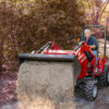Man uses a Massey Ferguson front loader tractor to dump fresh gravel on a road to protect it during the winter.