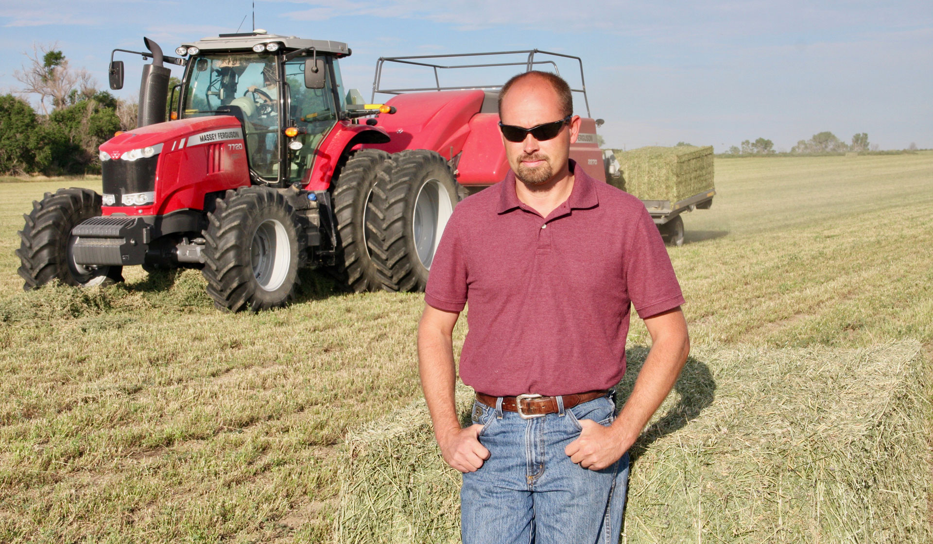 Farmer Rex Reyher stands in front of his red Hesston by Massey Ferguson 2270 baler.